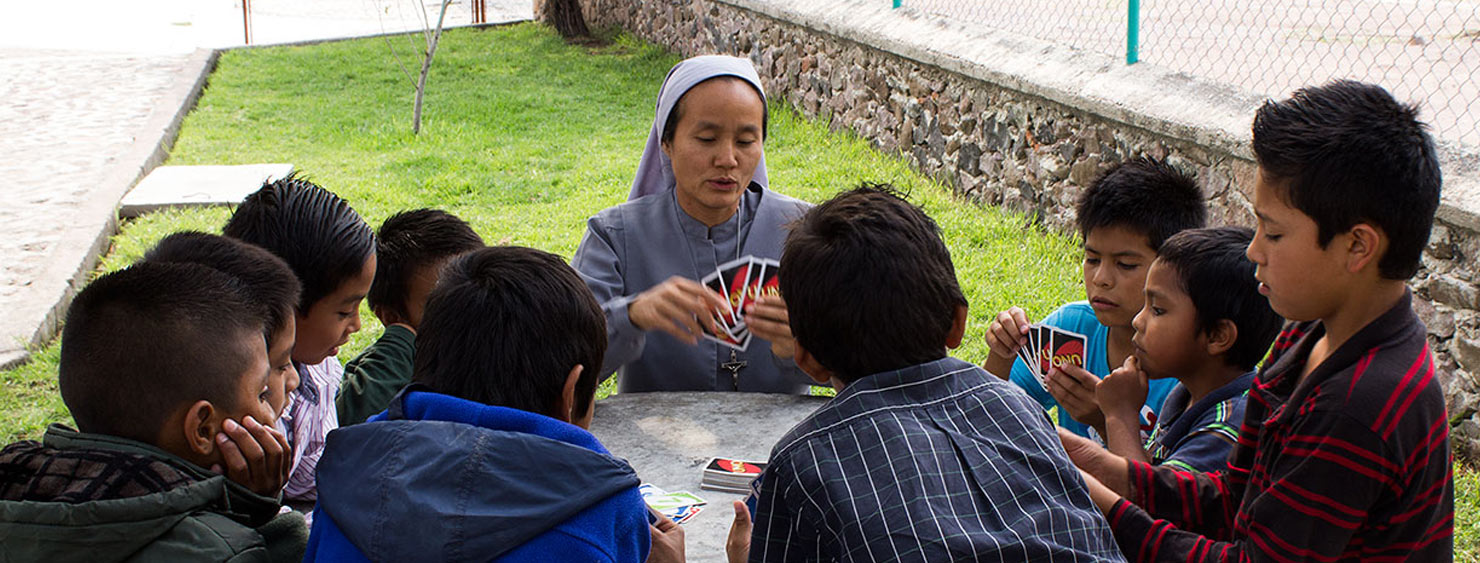 A volunteer plays cards with the children at Santa Maria del Mexicano